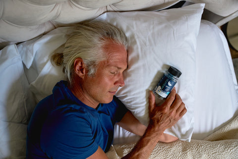 a man laying in bed holding a cell phone