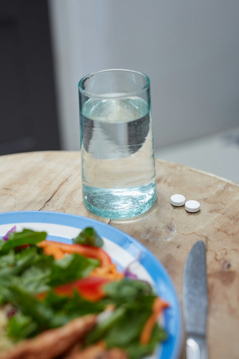 Water and pills with a healthy meal.